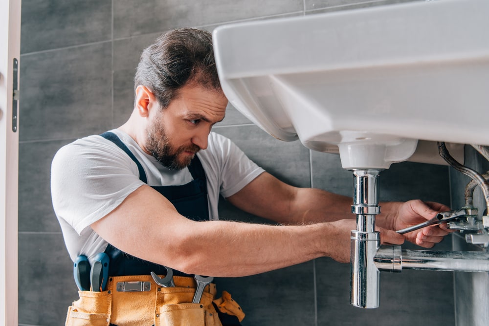 plumbing service specialist repairing drain pipes