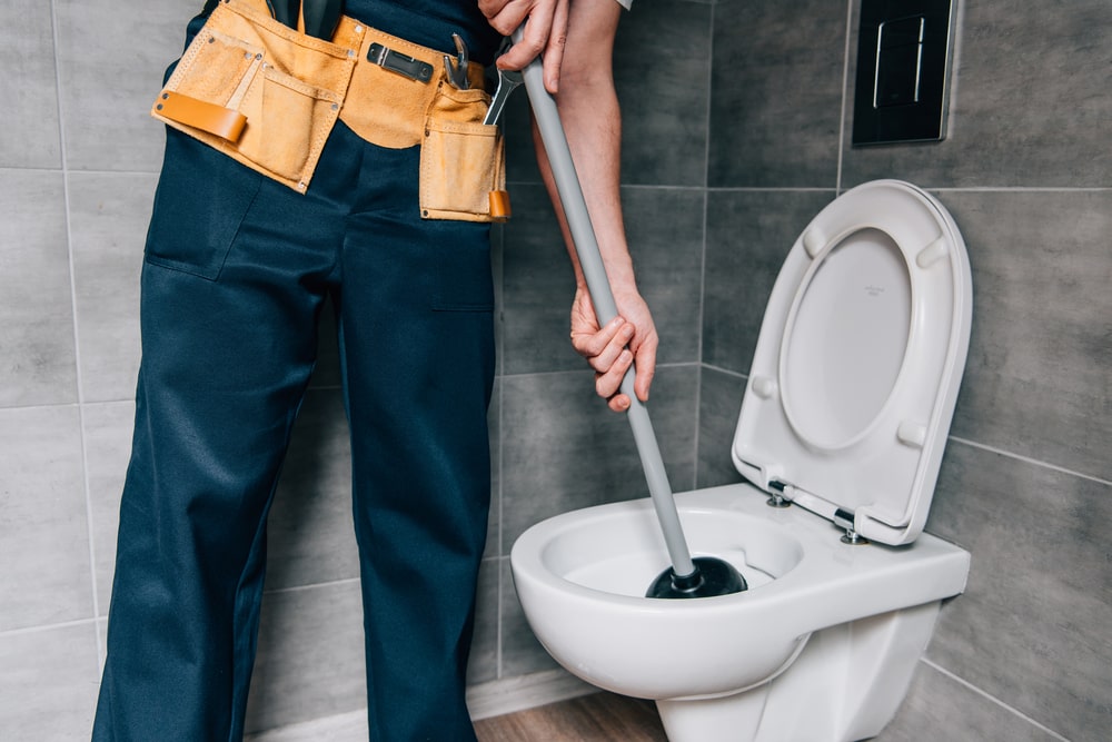 plumber cleaning toilet with plunger