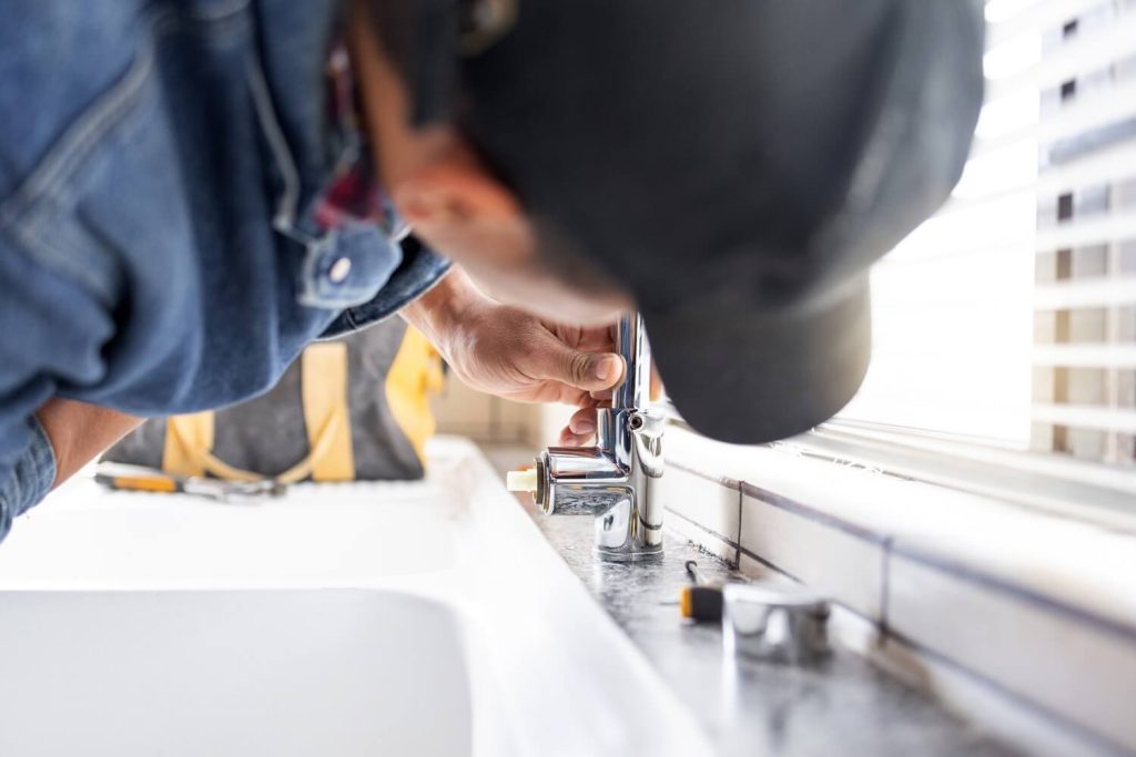 pro plumber repairing faucet leaks in the kitchen